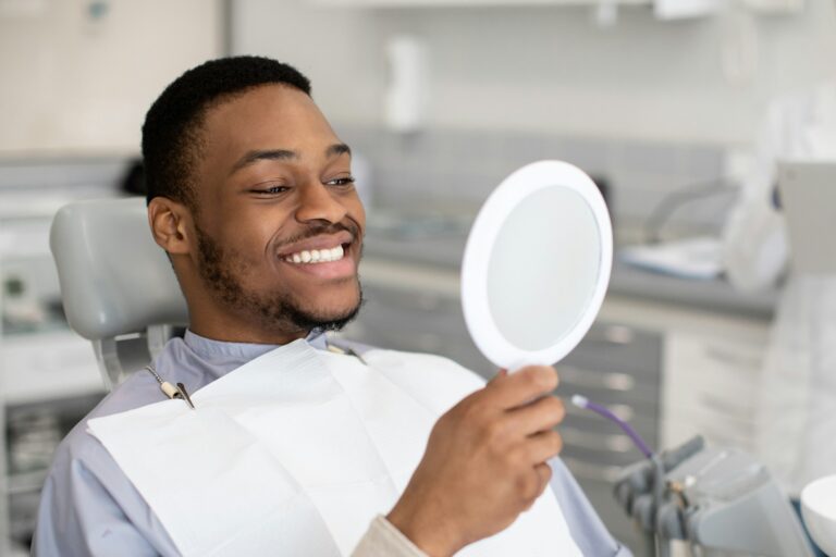 Portrait Of Happy Dental Clinic Patient Looking At Mirror After Treatment